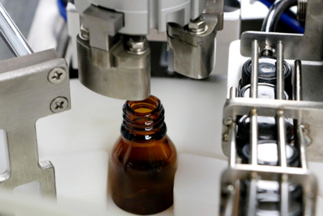 Mesin pengisian botol minyak di atas meja.jpg